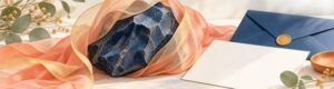 Donkerblauwe steen verzacht door koraal- en goudkleurige linten